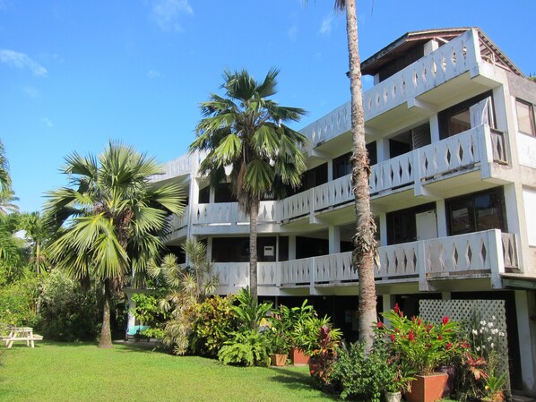 A multi-story hotel with balconies, surrounded by palm trees and various plants. - Raina Holiday Accommodation (Rarotonga)