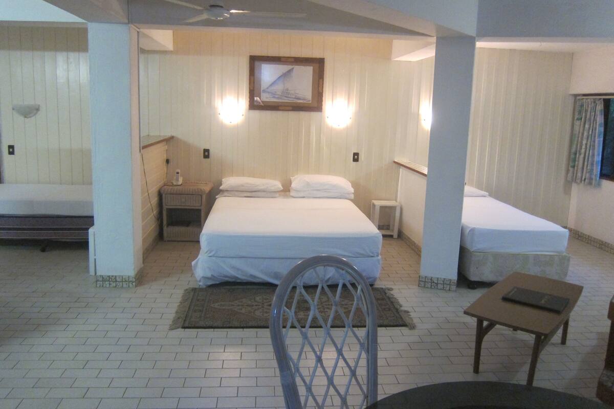 A hotel room with a bed, a chair, a small table, and a picture on the wall.