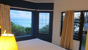 Una camera da letto con un letto, una finestra vista mare e una porta che dà all'esterno.