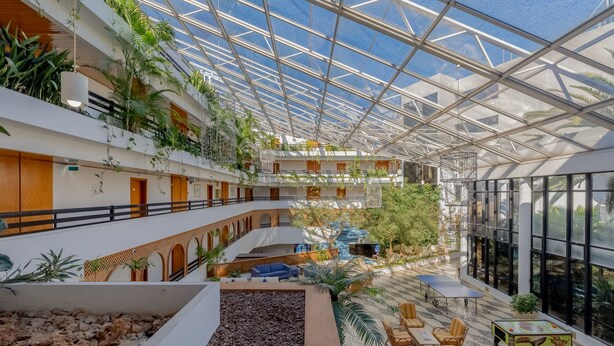A multi-level atrium with a glass ceiling, indoor plants, seating areas, and a pool. - Muthu Oura Praia Hotel (Albufeira)