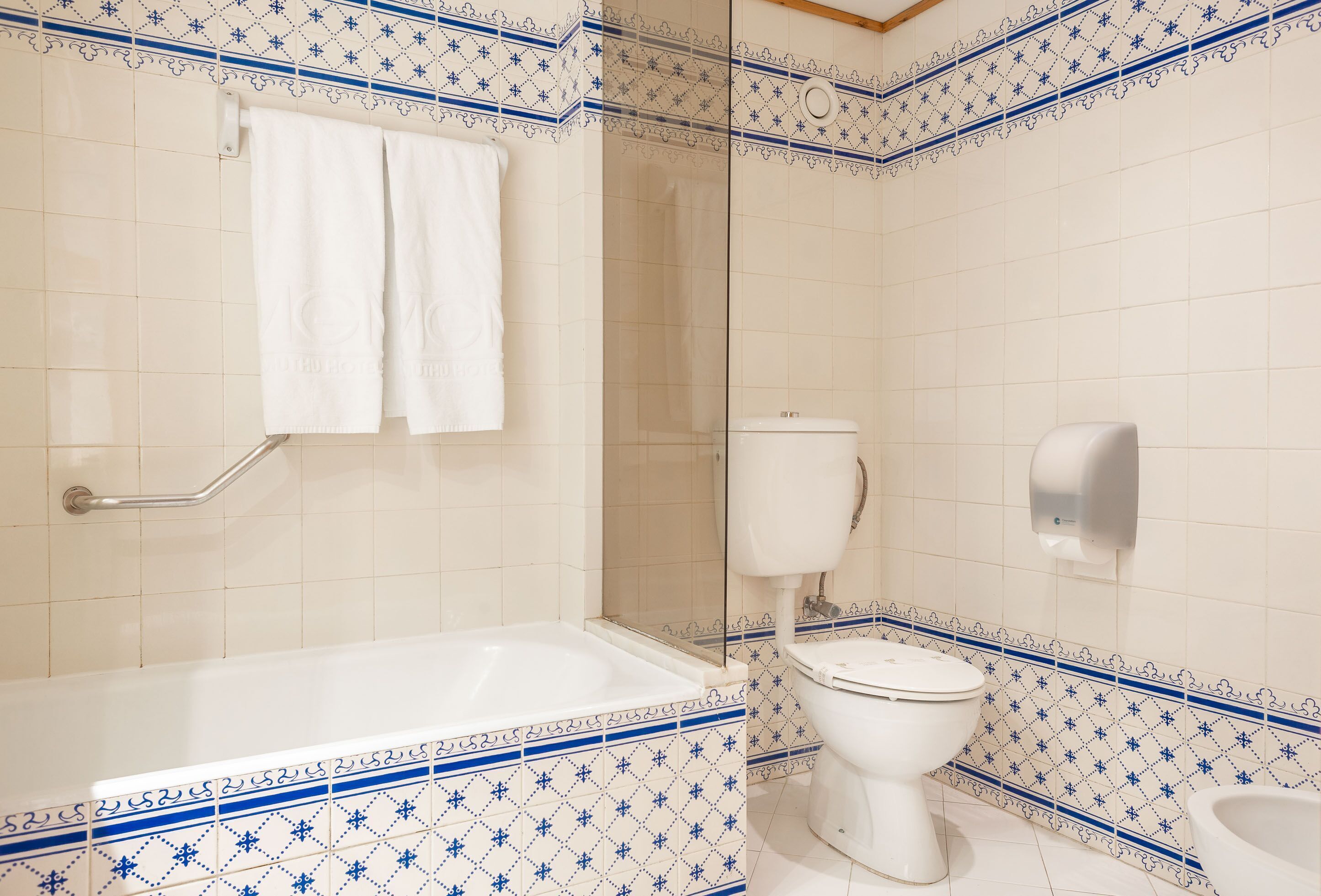 A bathroom with a bathtub, toilet, and hand dryer.