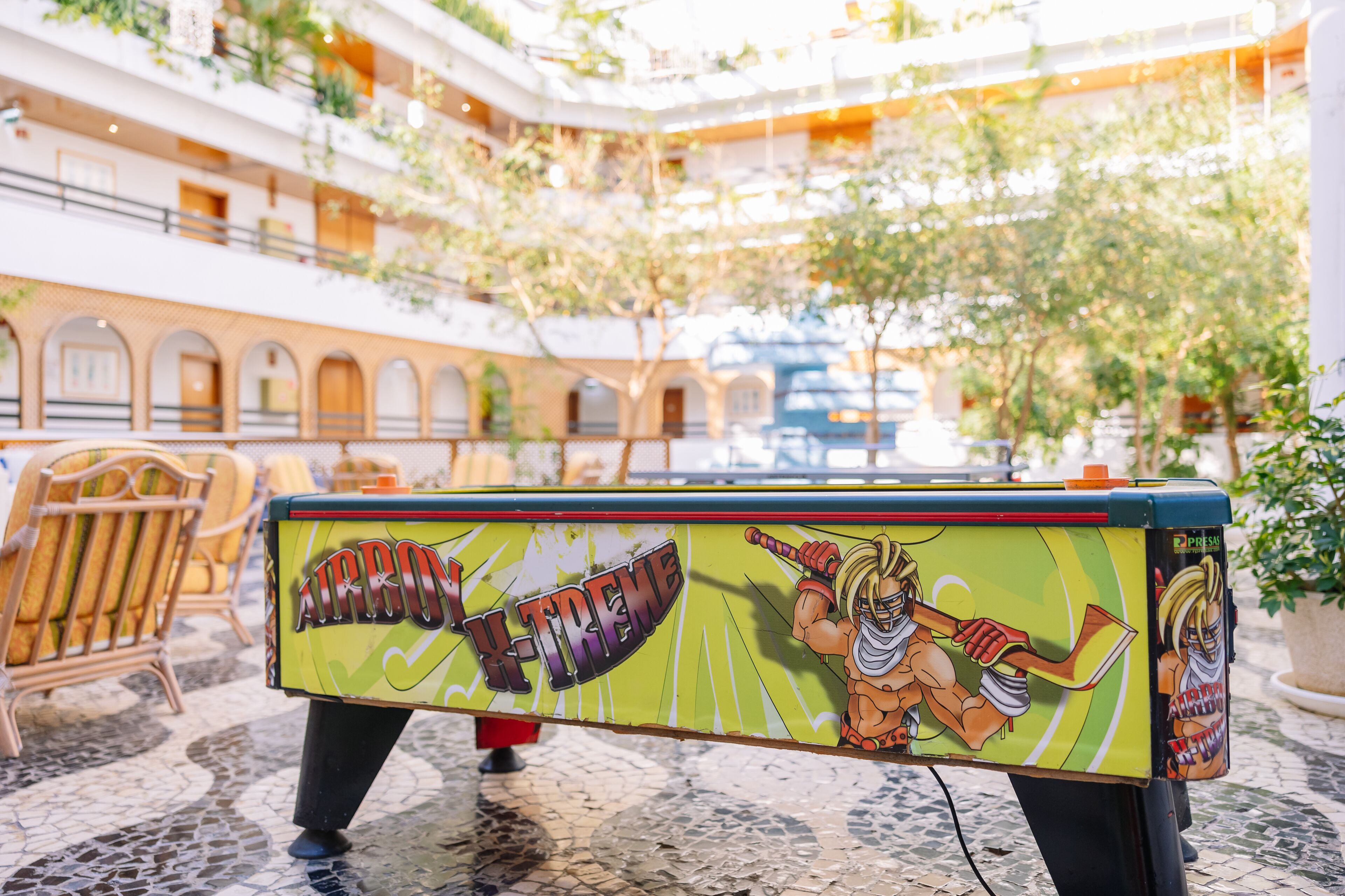 Una mesa de billar con un diseño 'X-TREME' en el vestíbulo de un hotel, con suelo de baldosas y plantas de interior.
