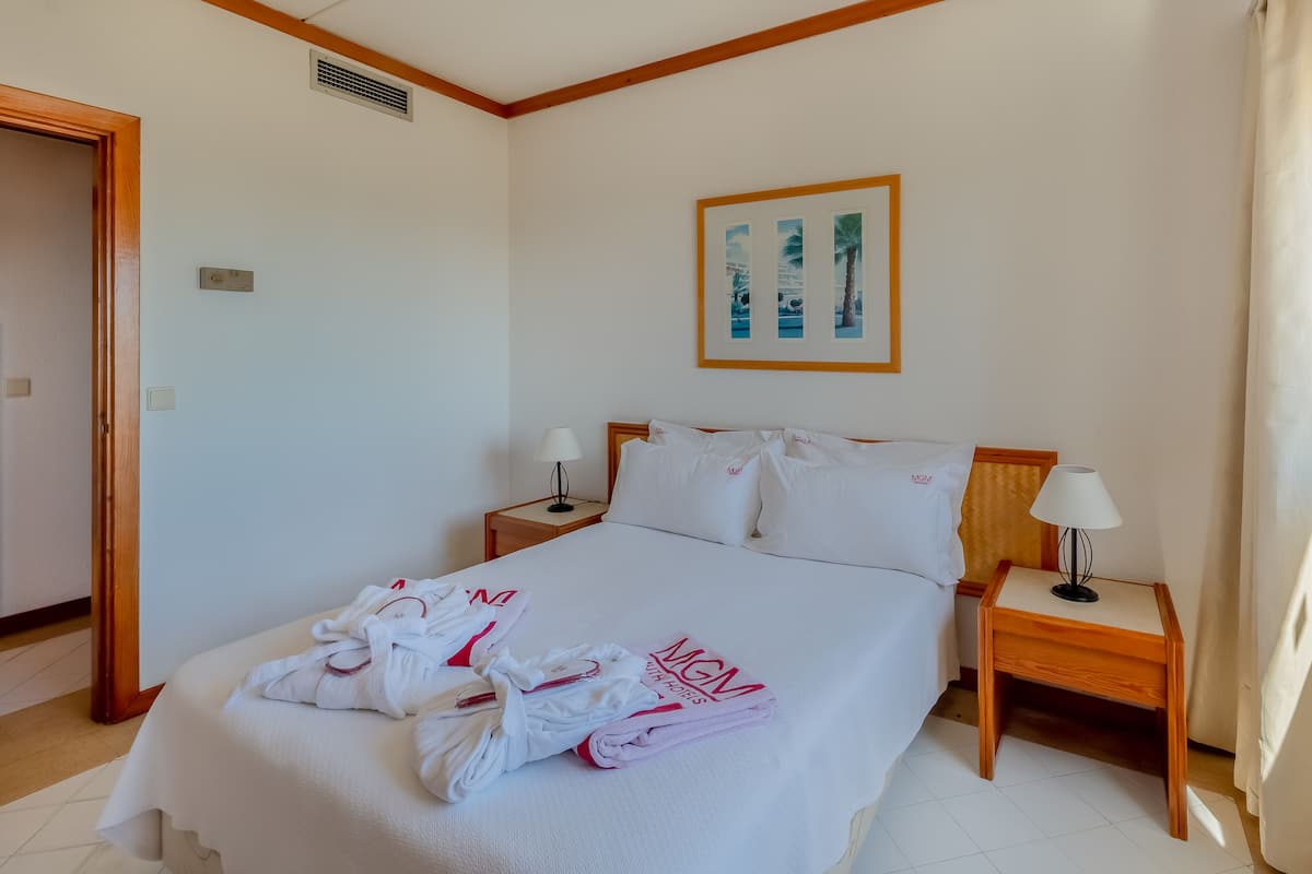 A hotel room with a neatly made bed, two bedside tables with lamps, and a framed picture on the wall.