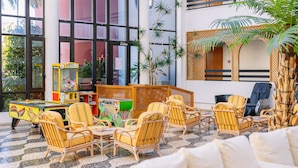A lobby with wicker chairs, a pool table, and a large window. - Muthu Oura Praia Hotel (Albufeira)