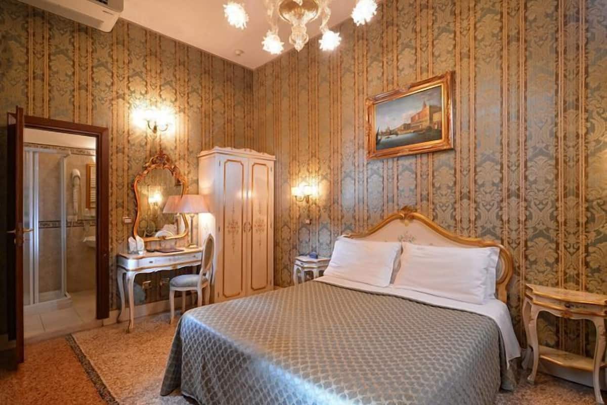 Une chambre avec un lit, un bureau, une armoire et un miroir.