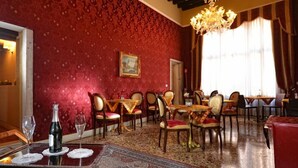 Un coin repas avec un papier peint à motifs rouges, des chaises en bois et un lustre.