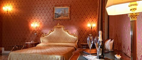 Een hotelkamer met een groot bed, een houten nachtkastje met een dienblad, en wandlampen.