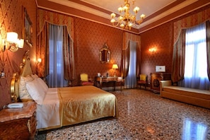 A spacious hotel room with a large bed, a desk, and a seating area.