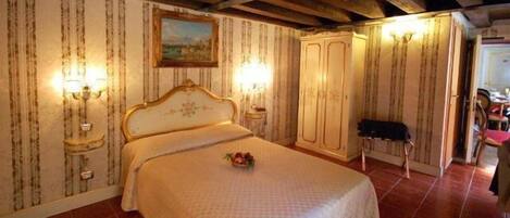 A bedroom with a bed, two wall-mounted lamps, a nightstand, a wardrobe, and a painting on the wall.