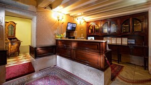 Un espace d’accueil doté d’un comptoir en bois, d’un téléviseur fixé au mur et d’un éclairage décoratif.