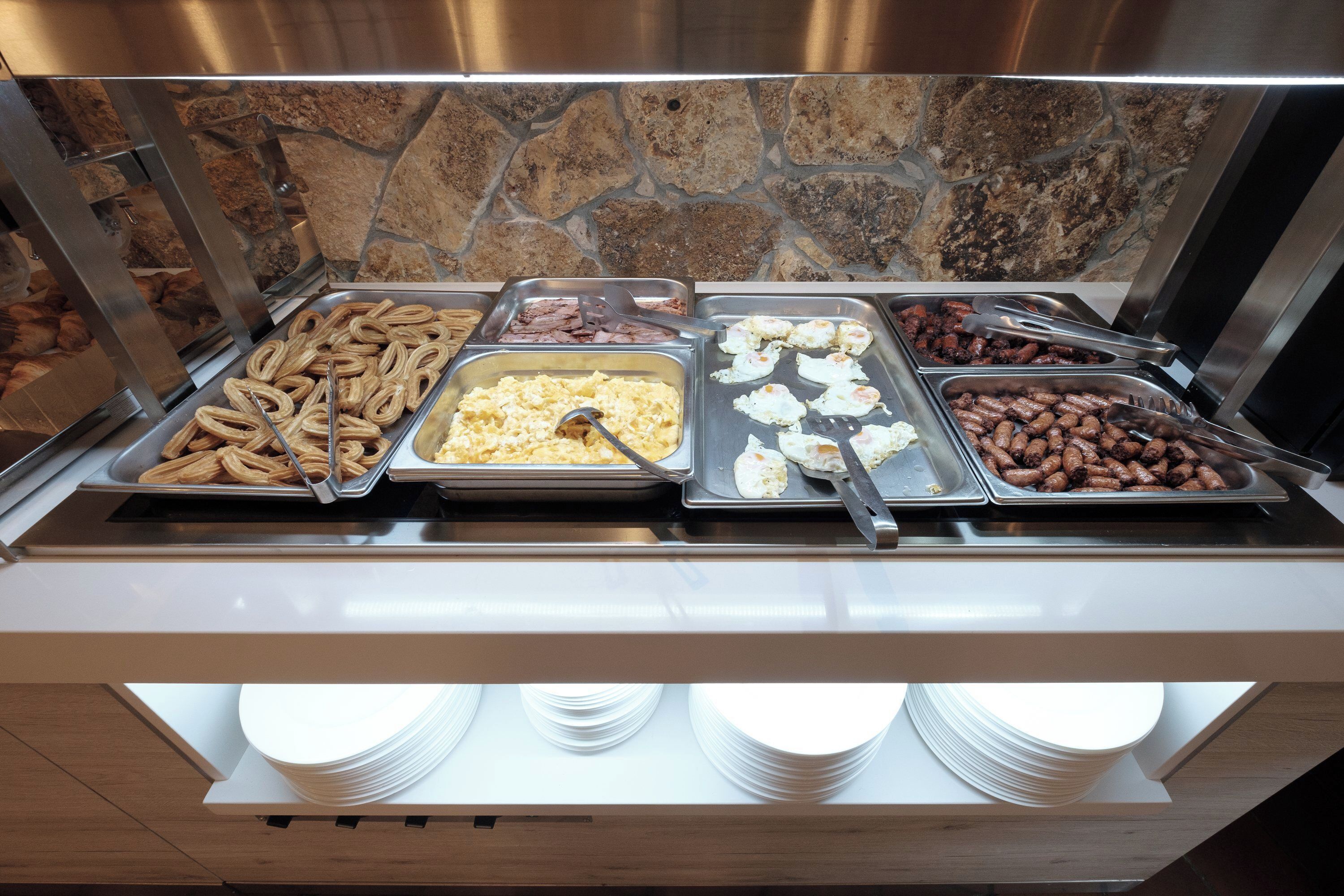 Un bufé con diversos alimentos, incluyendo salchichas, huevos y frijoles.