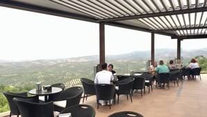 Een terras buiten met rieten meubilair en uitzicht op het landschap.