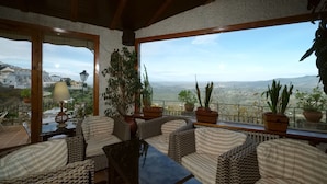 Een gezellig balkon met rieten meubilair, potplanten en uitzicht op het landschap.