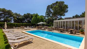Una piscina al aire libre, sillones reclinables de piscina