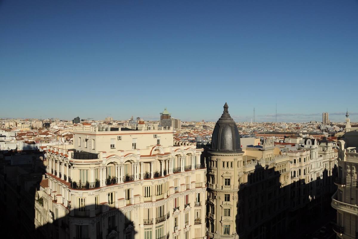 A high-rise building with a prominent dome and classical architecture, surrounded by other buildings in a densely populated urban area.