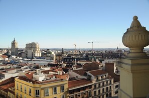 A cityscape with historic buildings, a prominent tower, and a construction crane in the distance. - Hostal Luis XV (Madrid)