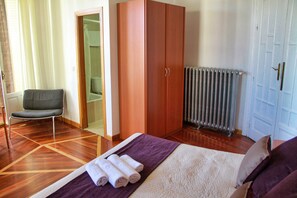 A bedroom with a bed, a wardrobe, a chair, and a radiator. - Hostal Luis XV (Madrid)