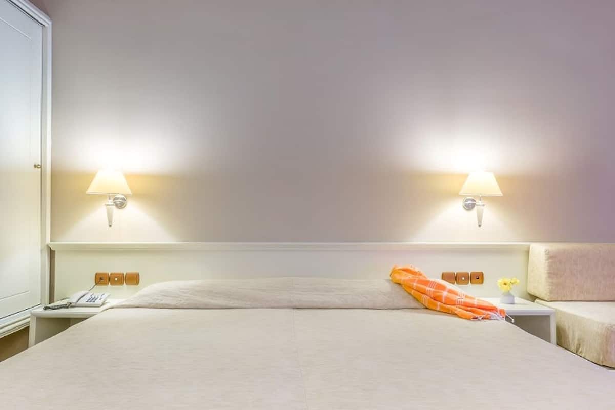 Hotelkamer met een groot bed, twee bedlampen, een telefoon en een klein tafeltje met een bloemenvaas.