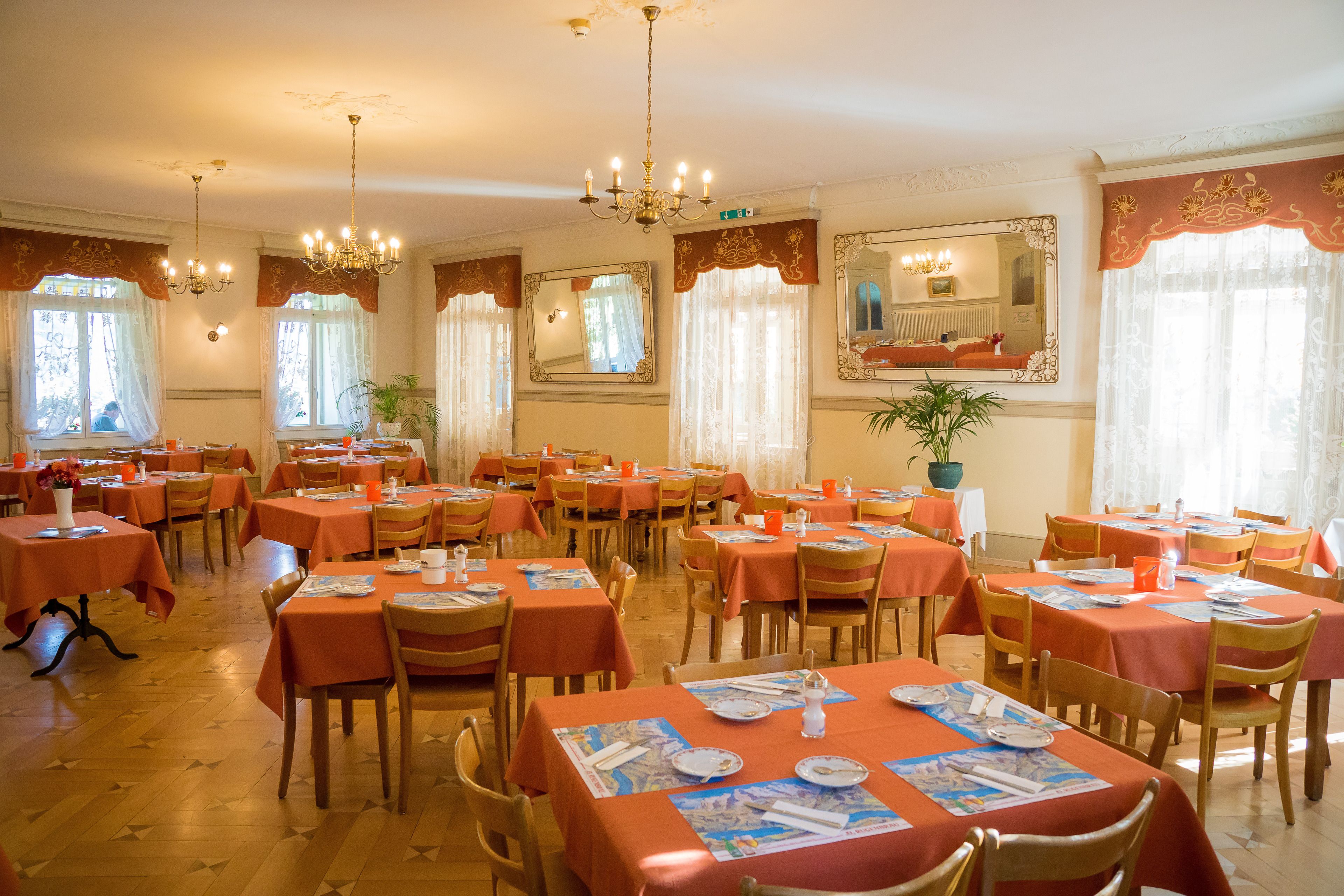 Comedor con varias mesas y sillas, cada una cubierta con un mantel.