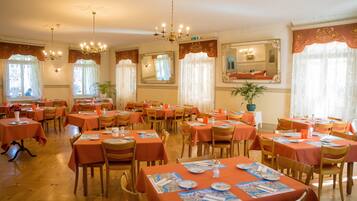 Comedor con varias mesas y sillas, cada una cubierta con un mantel.