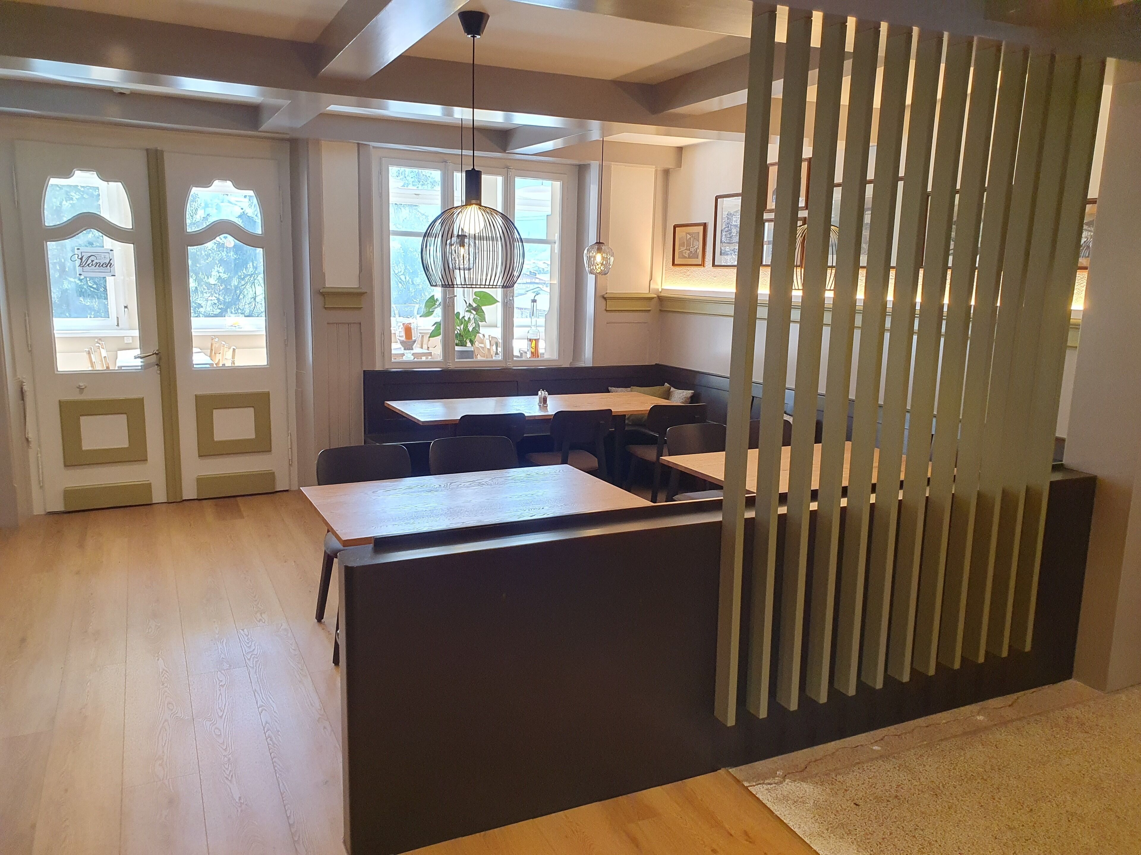 A modern interior with a dining area, kitchen, and a view through the window.