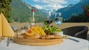 Un repas accompagné d’une bouteille de vin, de verres et d’une vue sur les montagnes.