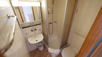 A small bathroom with a shower, sink, and toilet.