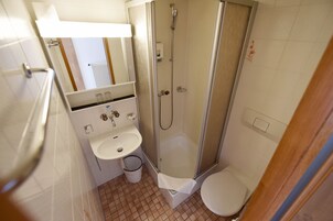 Un baño pequeño con ducha, lavabo e inodoro.