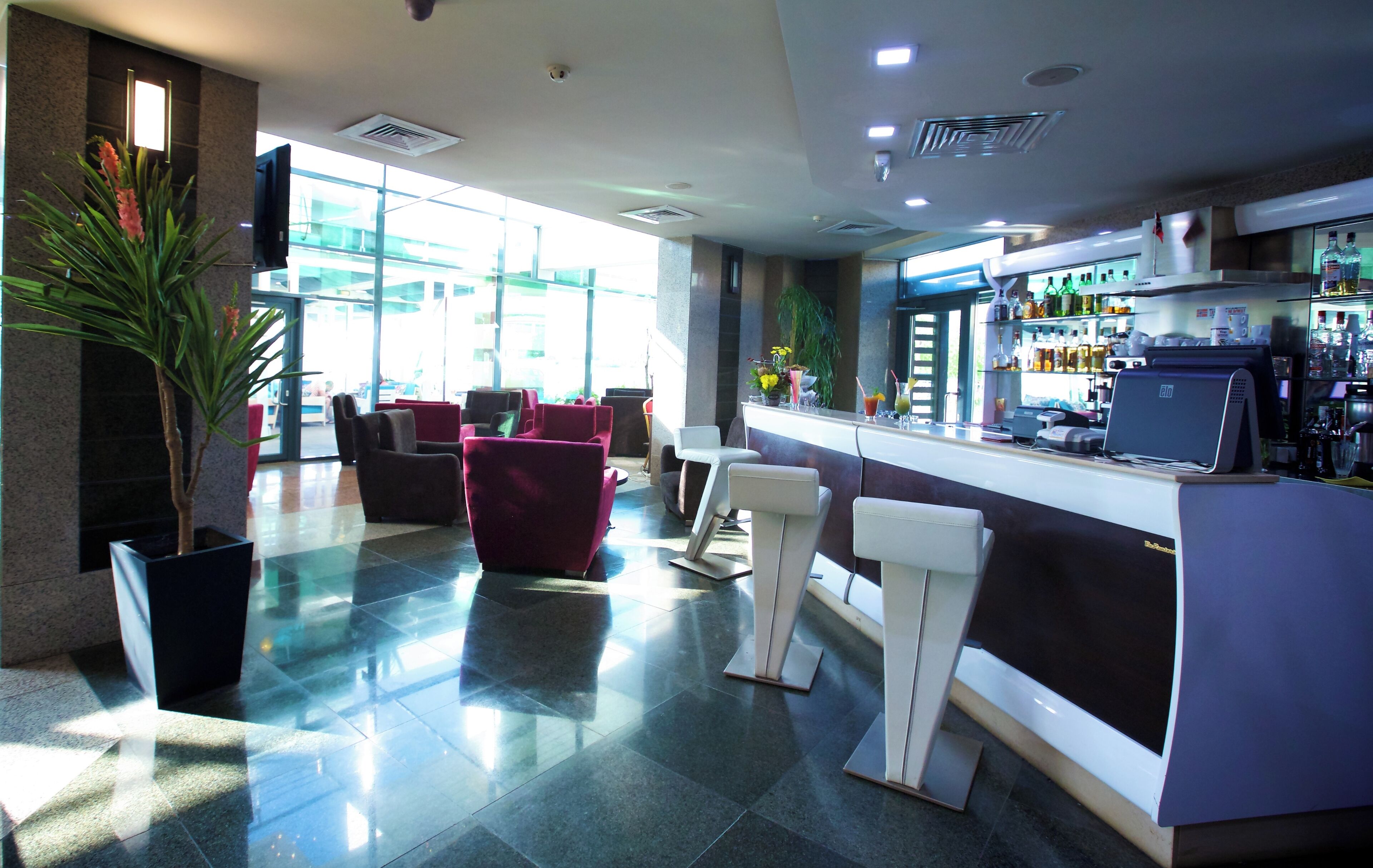 A hotel lobby with a bar area, seating, and a large window.