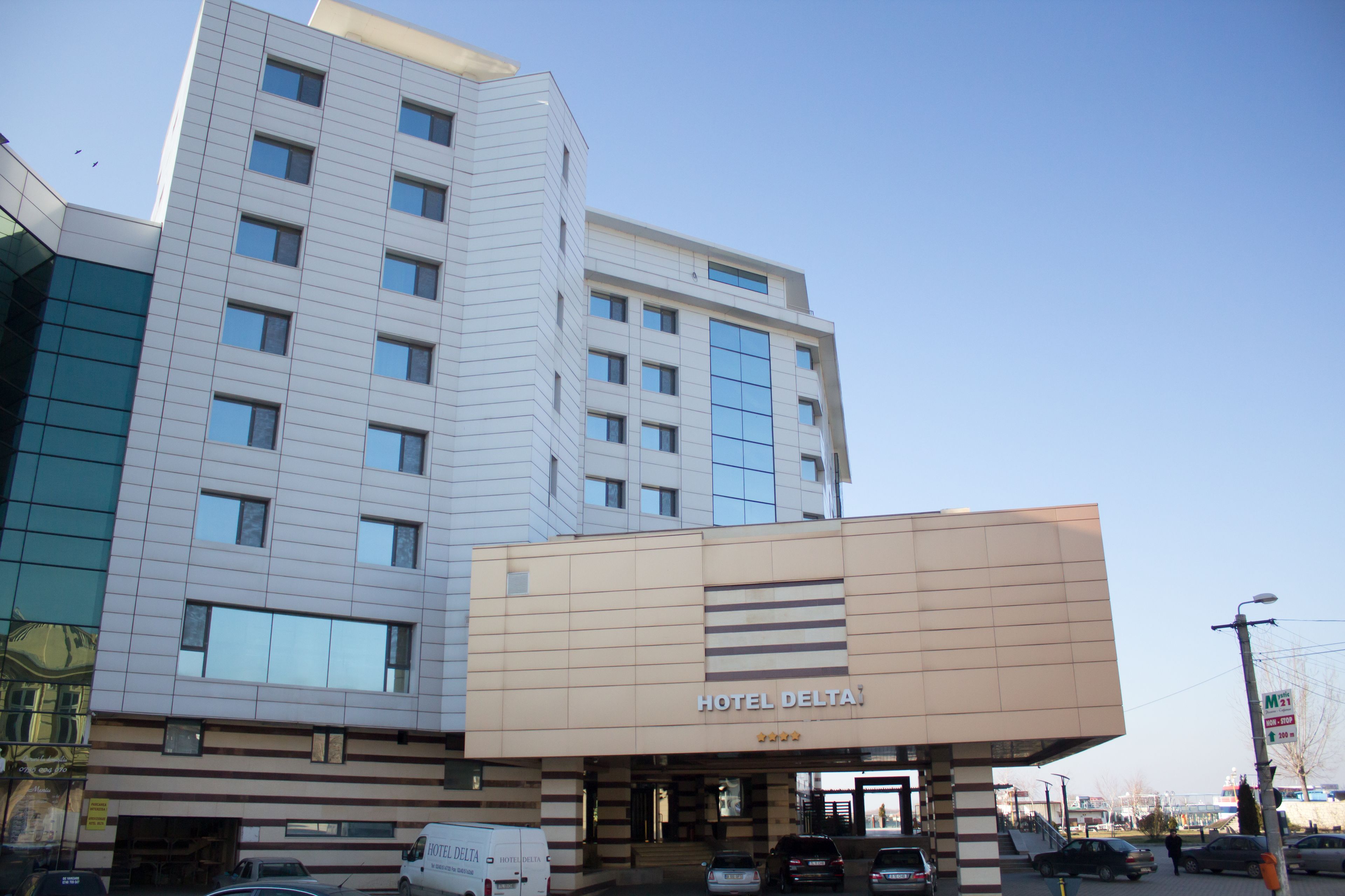 A multi-story hotel with a modern facade, a prominent entrance, and a visible parking area.