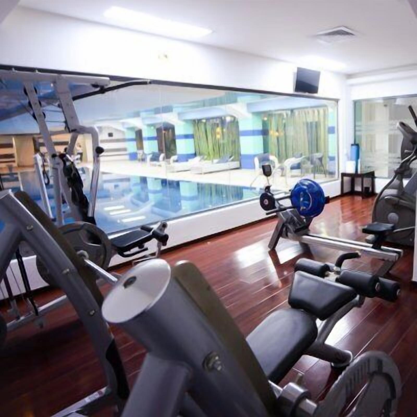 A gym with exercise equipment and a view of a pool area.