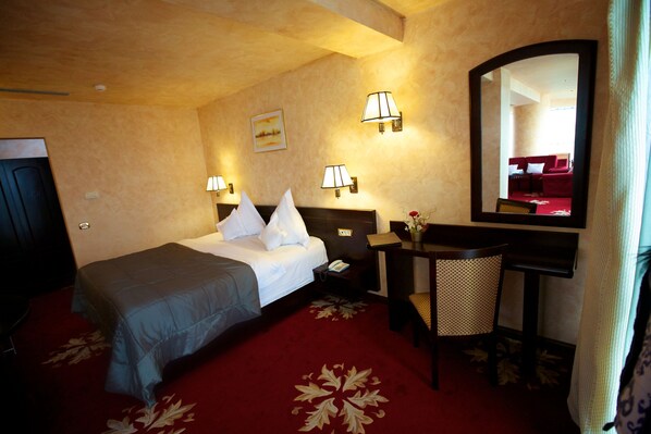 A hotel room with a bed, desk, chair, and a large mirror. - Delta 4 (Tulcea)