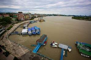 A riverfront with boats docked, a pedestrian walkway, and buildings in the background.