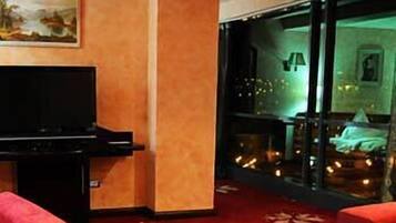 A hotel room with a flat-screen TV, a red carpet, and a balcony with a view.