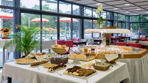 Disposição de buffet com diversos alimentos e uma planta em vaso.