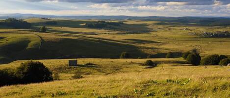 A panoramic view of rolling hills with a small building in the foreground.