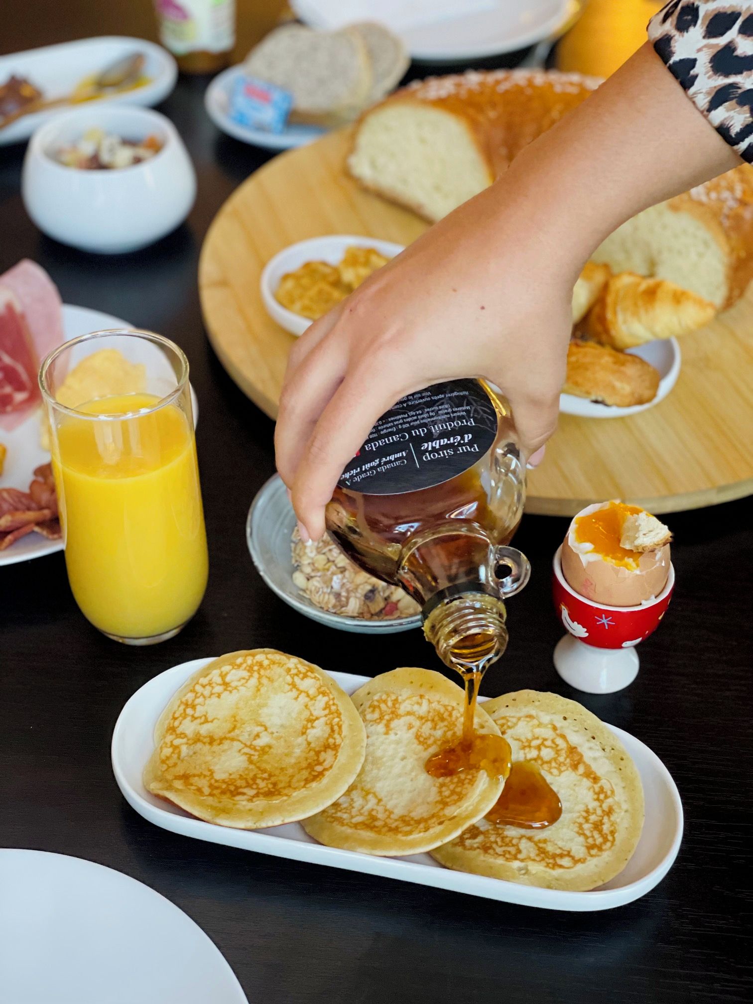 Een ontbijt met pannenkoeken, siroop en een glas sinaasappelsap.