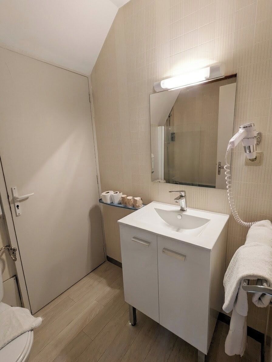 A bathroom with a white sink, a mirror, a towel rack, and a hairdryer.