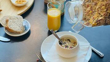 Un desayuno con diversas opciones de comida y un vaso de jugo de naranja sobre una mesa.