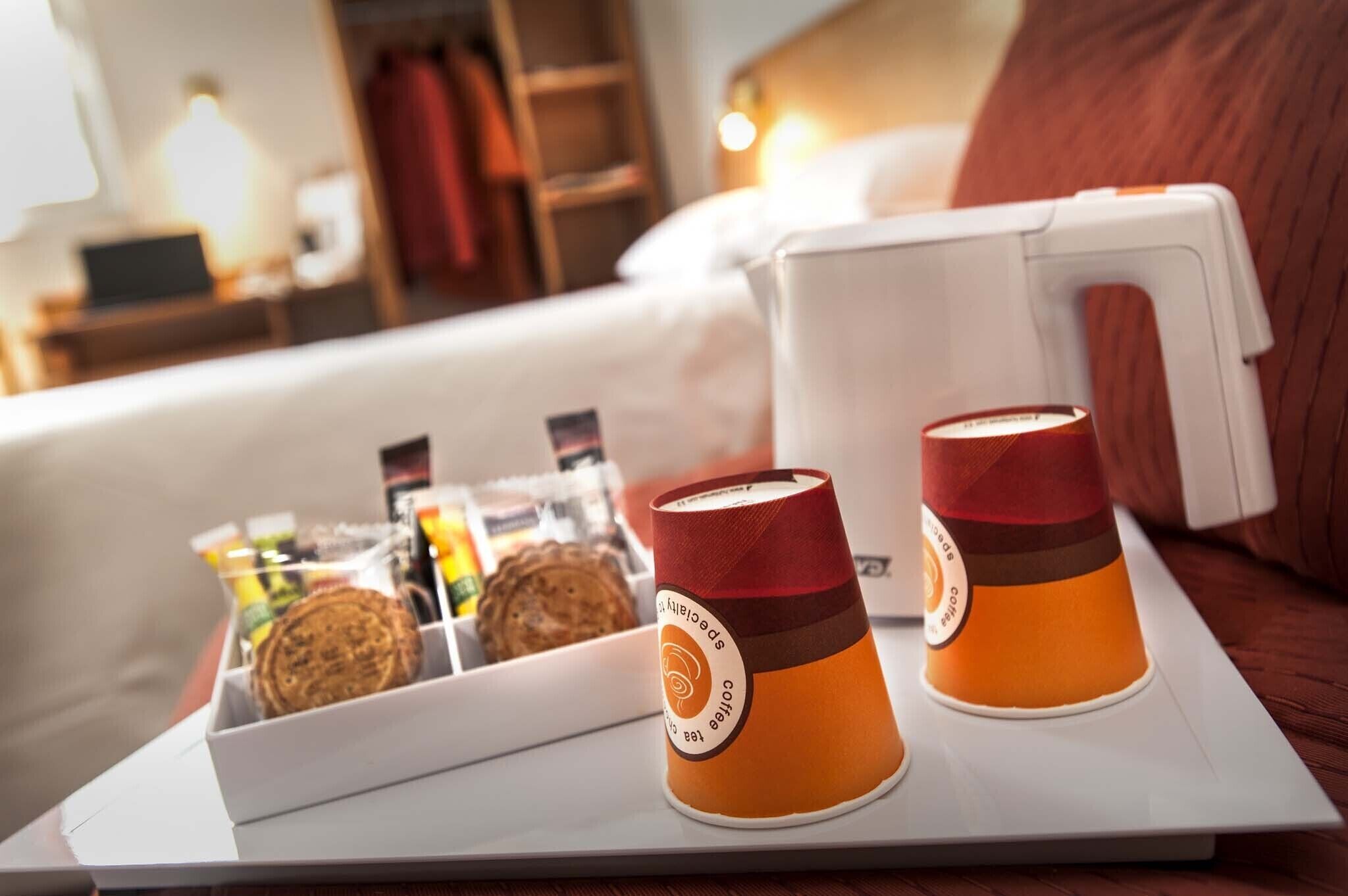 A tray with two coffee cups and a container of cookies on a hotel room table.