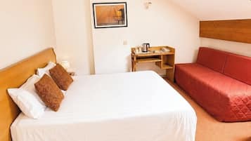Een slaapkamer met een bed, een rode bank, een houten nachtkastje, een ingelijst schilderij aan de muur en een schuin plafond.