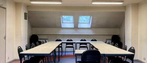A conference room with a long table, black chairs, and two skylights.