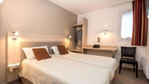 Een hotelkamer met een groot bed, nachtkastjes, een bureau en een stoel.