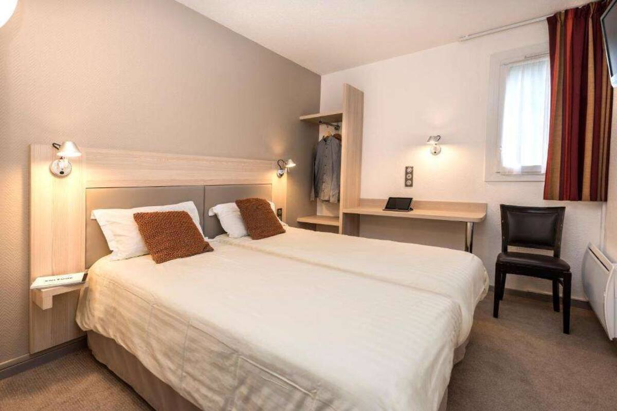 Ein Hotelzimmer mit einem großen Bett, Nachttischen, einem Schreibtisch und einem Sessel.