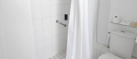 Un baño con ducha, inodoro y un estante con artículos de aseo.