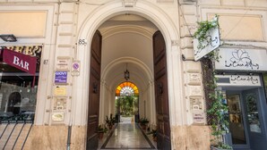 Entrada de hotel con un arco, plantas en macetas y un letrero que dice 'La Casa di Mamma'.