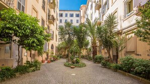 Un patio empedrado con plantas en macetas y una fuente en el centro.