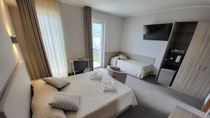 A hotel room with two beds, a desk, a TV, and a wardrobe. - Hotel Rosmari (Brenzone sul Garda)