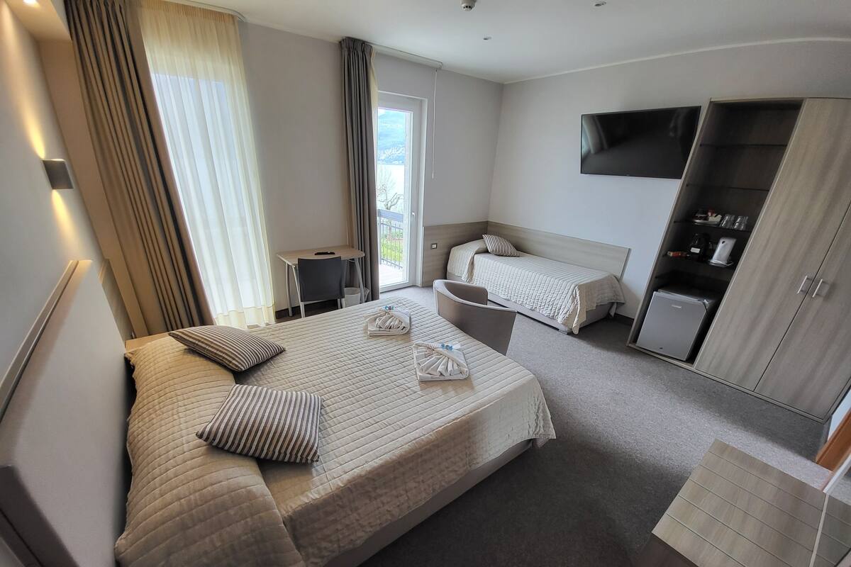 A hotel room with two beds, a desk, a TV, and a wardrobe.