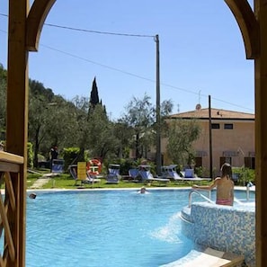 Relax by the pool with lounge chairs and umbrellas, surrounded by a hotel building and scenic views.